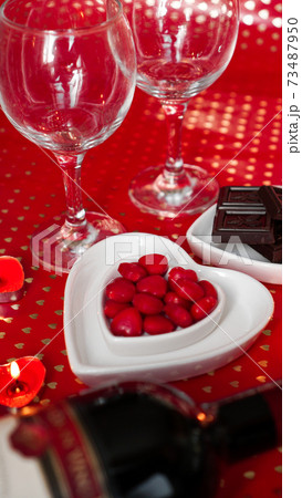 Valentines day. Bottle of vine, glasses, red roses, candles - red background Valentines day. Bottle of vine, glasses, red roses, candles - red background 73487950