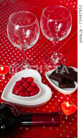 Valentines day. Bottle of vine, glasses, red roses, candles - red background 73487952