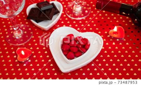 Valentines day. Bottle of vine, glasses, red roses, candles - red background 73487953