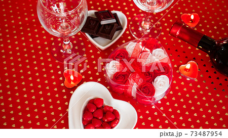Valentines day. Bottle of vine, glasses, red roses, candles - red background 73487954