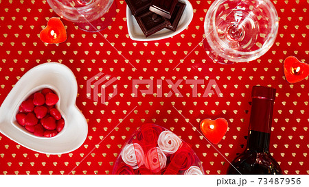 Valentines day. Bottle of vine, glasses, red roses, candles - red background Valentines day. Bottle of vine, glasses, red roses, candles - red background 73487956