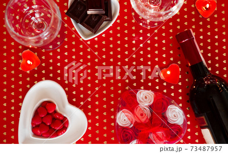 Valentines day. Bottle of vine, glasses, red roses, candles - red background Valentines day. Bottle of vine, glasses, red roses, candles - red background 73487957