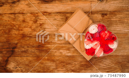 Letters in craft paper envelopes and a gift of roses on wooden background Letters in craft paper envelopes and a gift of roses on wooden background 73487990