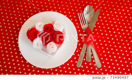 A white plate with a knife and fork on a bright red background A white plate with a knife and fork on a bright red background 73490497