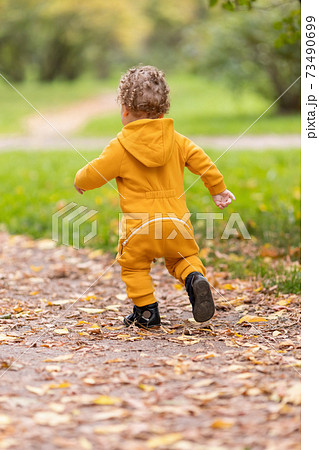 Little boy in yellow overalls walking first steps in autumn park Little boy in yellow overalls walking first steps in autumn park 73490699