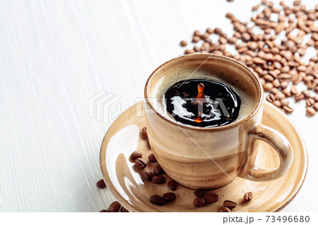 Black coffee and coffee beans on a white wooden table. 73496680