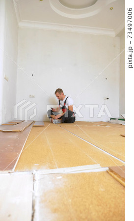 Builder in renovated room lying on floor using smartphone 73497006
