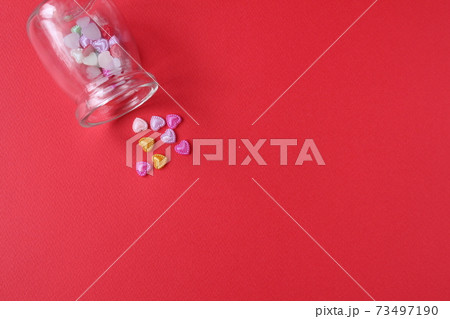 Rhine pink yellow hearted cards poured out of a glass can of flasks on a red background with a copyspace valentine's day Rhine pink yellow hearted cards poured out of a glass can of flasks on a red background with a copyspace valentine's day 73497190