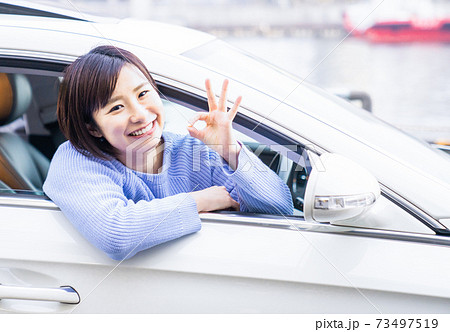 車の運転席でokマークをする若い女性の写真素材