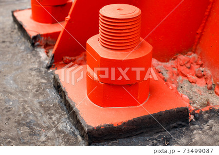 The red metal support is bolted to the concrete base with large bolts. Fixing a tower or tower to 73499087