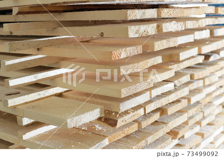 Wooden boards are stacked in a sawmill or carpentry shop. Drying and marketing of wood. 73499092