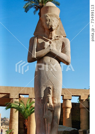 Unidentified male tourist walking towards the Colossal statue of pharaoh Rameses II and Princess-Queen Meritamen at Luxor Temple, dated back 1400 BC. Luxor Egypt. UNESCO World Heritage Site. 73499113