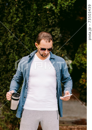 Man wearing white t-shirt holding phone mockup 73503439