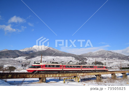北志賀の雪山をバックに夜間瀬橋を渡る長野電鉄特急ゆけむり 73505025