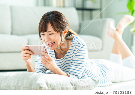 リビングで動画を見る若い女性 73505188