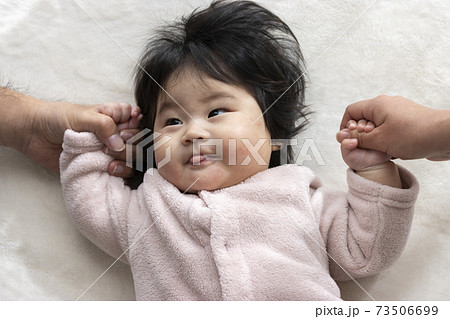 両親と手をつなぐ赤ちゃん 0歳 生後6カ月 日本人 女の子 の写真素材