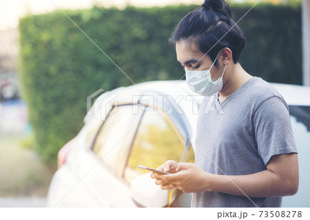 Asia man wearing a medical mask and using a phone outdoors 73508278