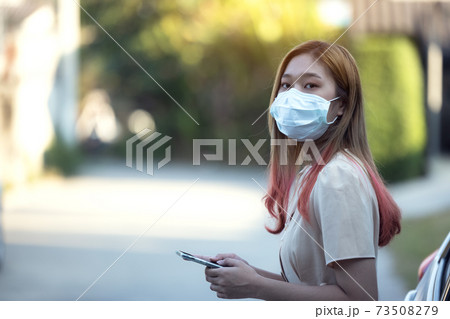 Asia woman wearing a medical mask and using a phone outdoors 73508279