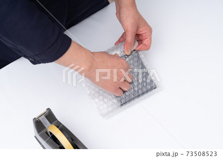 梱包作業をする女性の手元 73508523