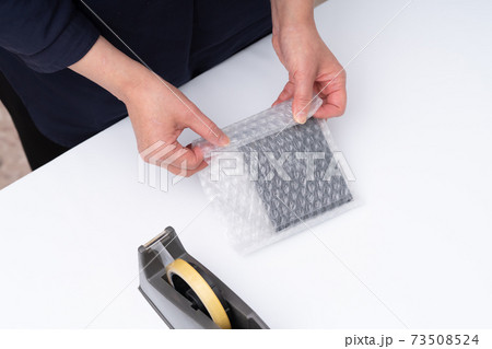 梱包作業をする女性の手元 73508524