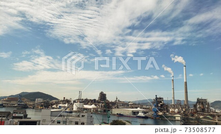 煙突から煙が出ている工場地帯の景色・環境保護と生産活動の両立・青空の下の工場地帯・高度経済成長・車窓 73508577