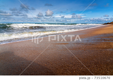 Sandy beach, small waves and blue sky with clouds Sandy beach, small waves and blue sky with clouds 73510670