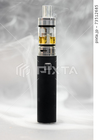 Electronic cigarette against background full of smoke 73512685