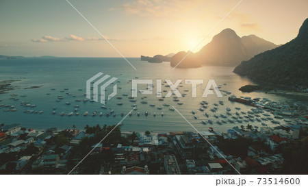 Aerial sunset at ocean harbor with boats of tropic port town cityscape. Buildings, lodges, homes Aerial sunset at ocean harbor with boats of tropic port town cityscape. Buildings, lodges, homes 73514600