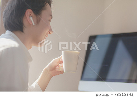 コーヒーをに見ながらパソコンで作業する青年 コーヒーをに見ながらパソコンで作業する青年 73515342