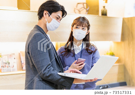 オフィスで打ち合わせをするマスクをした若い男女 オフィスで打ち合わせをするマスクをした若い男女 73517331