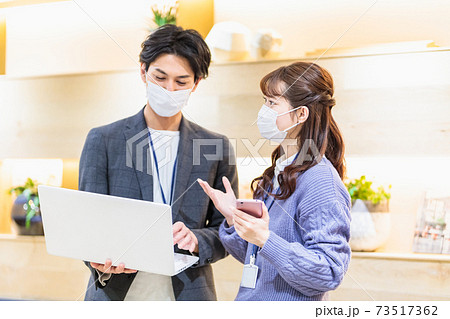 オフィスで打ち合わせをするマスクをした若い男女 オフィスで打ち合わせをするマスクをした若い男女 73517362