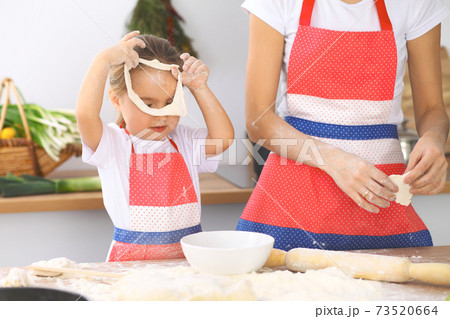 Mother and her cute daughter prepares the dough at wooden table. Homemade pastry for bread or pizza. Bakery background Mother and her cute daughter prepares the dough at wooden table. Homemade pastry for bread or pizza. Bakery background 73520664
