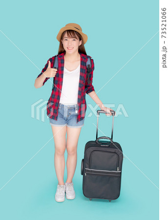 Beautiful young asian woman pulling suitcase isolated on blue background. 73521066