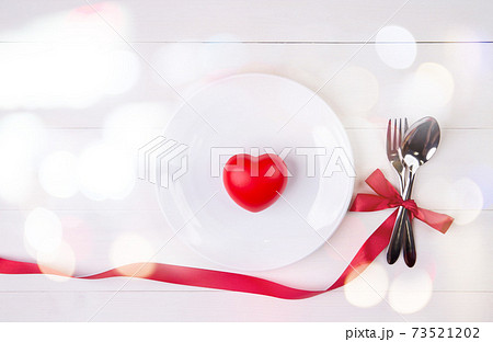Valentine day, heart shape on dish and utensil with bow for dinner on wooden table. 73521202