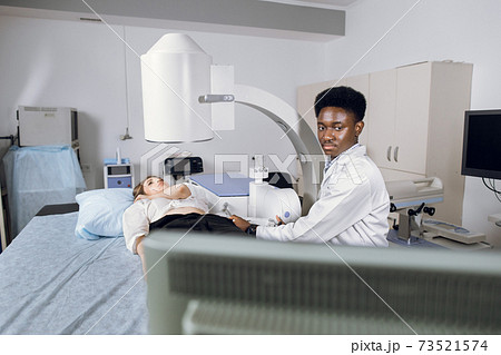 Lithotripsy for kidney and ureteral stones in modern center. Professional African man doctor, using ultrasound scan to determine the stone position before the lithotripsy for his female patient 73521574