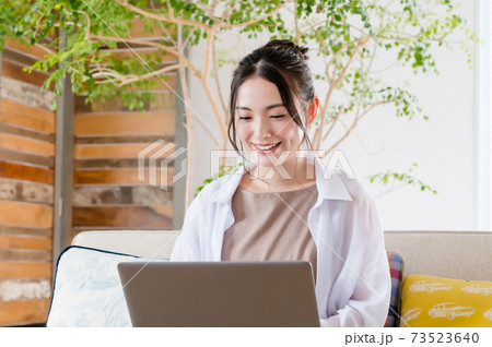 ソファで座ってテレワークする若い女性 ソファで座ってテレワークする若い女性 73523640