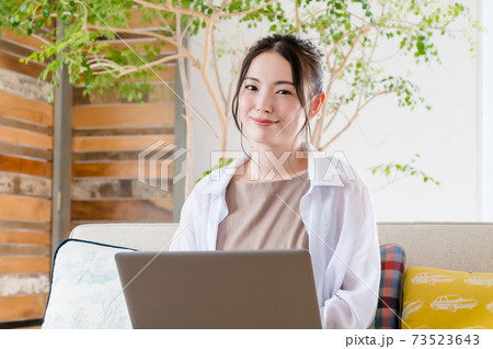 ソファで座ってテレワークする若い女性 ソファで座ってテレワークする若い女性 73523643