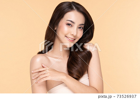 Beautiful Young Asian Woman Looking While Touching Shoulder feeling so happy and cheerful with healthy Clean and Fresh skin,isolated on Beige background,Beauty Cosmetology Concept 73526937