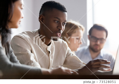 Focused young african employee working on computer with old colleague. Focused young african employee working on computer with old colleague. 73528051