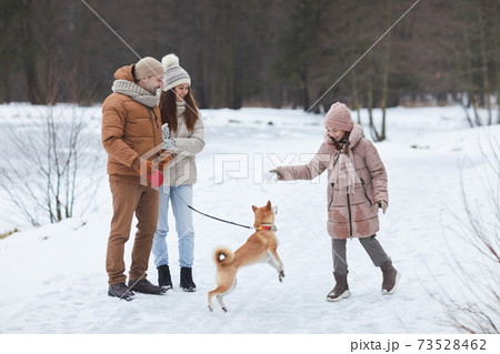 Joyful Family Walking Dog in Winter 73528462