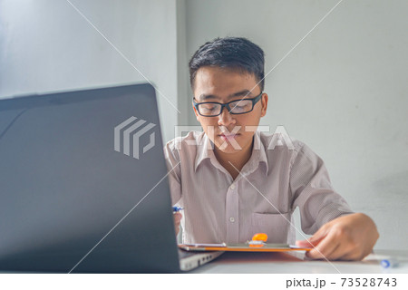 Asian financial executive working on laptop and data document 73528743