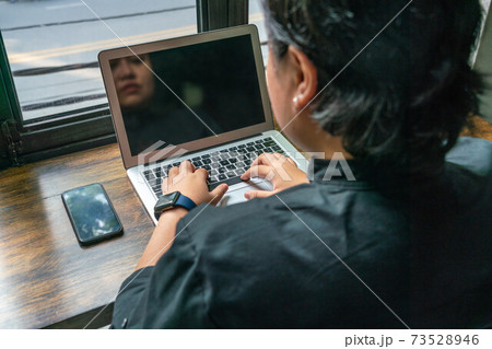 Rear view of Asian lesbian using laptop next to cellphone Rear view of Asian lesbian using laptop next to cellphone 73528946