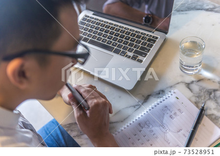 Young office man in glasses looking at mind mapping notebook Young office man in glasses looking at mind mapping notebook 73528951