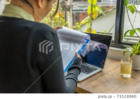 Woman working with document and laptop in garden view office 73528960