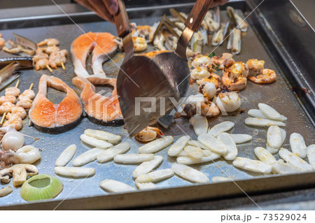Chef using spatula cooking assorted seafood in restaurant's kitchen Chef using spatula cooking assorted seafood in restaurant's kitchen 73529024