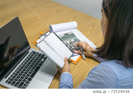 Asian office woman calculate financial number on document 73529436