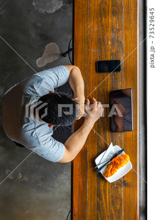 High angle view of Asian businessman using tablet next to smartphone High angle view of Asian businessman using tablet next to smartphone 73529645