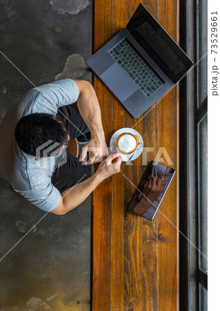Vertical photo of muscled freelancer using laptop and drinking coffee 73529661