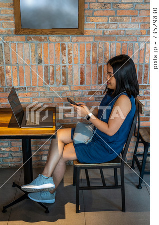 Young Asian woman sitting with laptop on wooden table 73529830