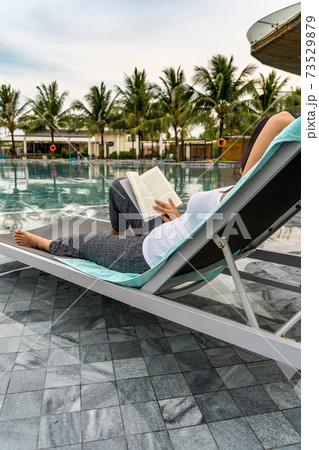Asian woman reading good book at swimming pool on vacation Asian woman reading good book at swimming pool on vacation 73529879